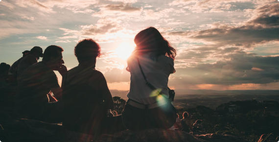 Grupa ludzi oglądająca zachód słońca