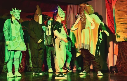 Grupa uczniów przebranych w kostiumy zwierząt stoi na scenie teatralnej w ośrodku specjalnym w Bochni.